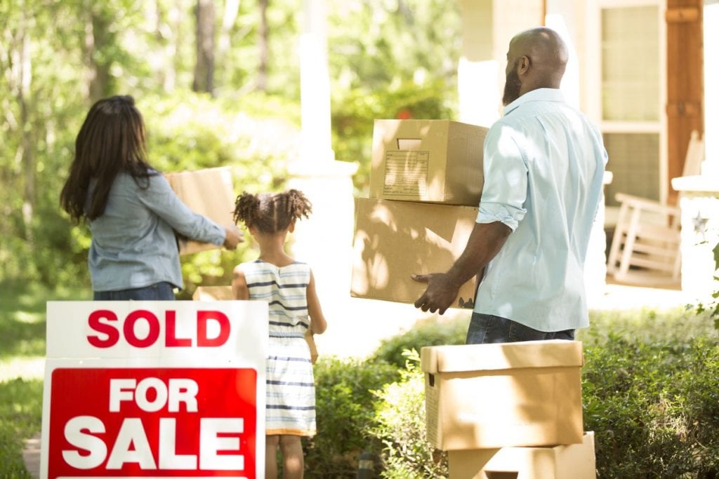 Family of homebuyers moving into new home with sold sign in yard