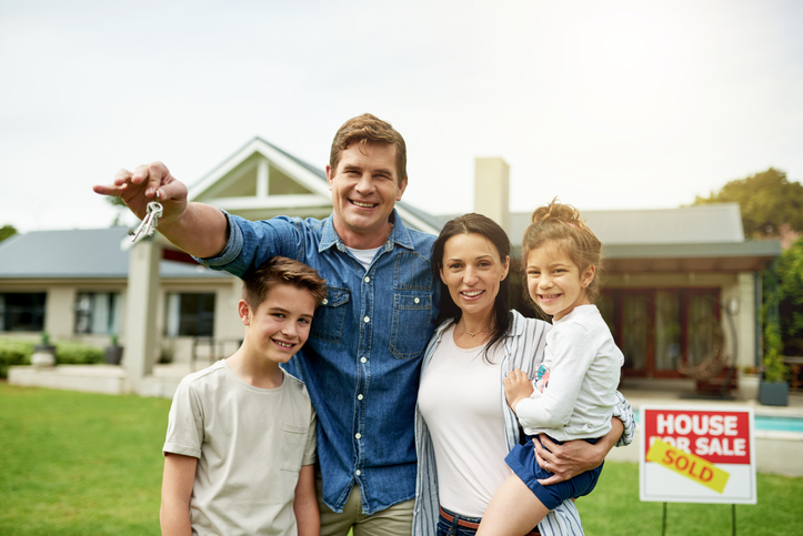 Family looks at new home they purchased with house for sale sign in yard