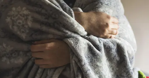 Person cuddled up in a warm blanket
