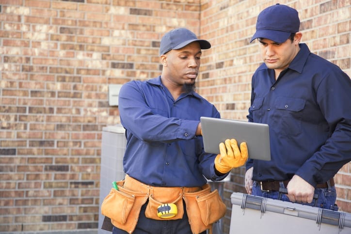 Technicians consulting work order for an air conditioning repair, which is covered by AFC's service contracts