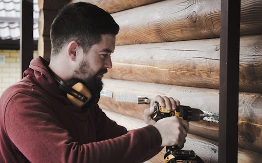 man using cordless drill to install home appliance